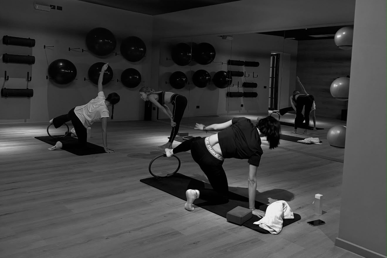 Lezione di Pilates Matwork in sala: tre persone al lavoro sul tappetino con il ring